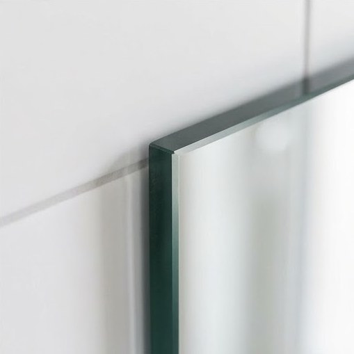 Geschliffene und polierte Spiegelkante im Detail vor heller Fliesenwand