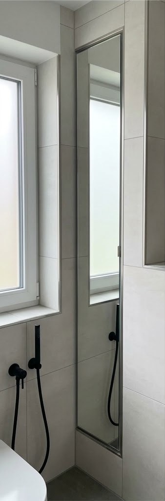 Schmaler Spiegel nach Maß in einer Wandnische neben dem Fenster in der Dusche
